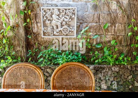 Steinbildhauerei an der Wand mit Blumenmuster und menschlichen Charakter in balinesischem Stil, Kuta, Bali, Indonesien. Stockfoto