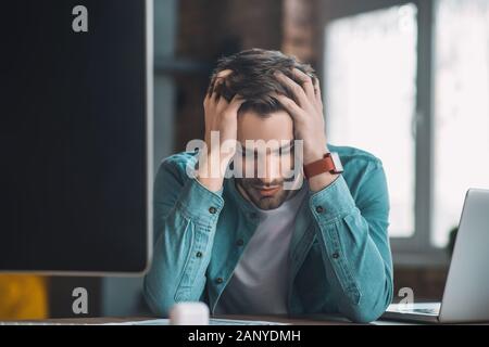 Gut aussehende junge Mann seinen Kopf Holding Stockfoto