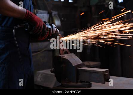 Metallarbeiter, die in der Produktionsstätte Energiewerkzeuge verwenden, schneiden und Formen von Metall während der Arbeitsschicht - Ansicht von Studenten der Ingenieurbranche, die Hochleistungsgeräte in der Werkstatt verwenden Stockfoto