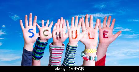 Kinder Hände Gebäude Bunte deutsche Wort Schule bedeutet. Blauen Himmel als Hintergrund Stockfoto