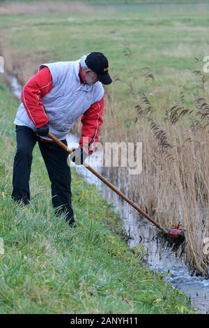 Nordenham, Deutschland. 18 Jan, 2020. Eine Bossel Player verwendet eine Krabbe (einem metallkorb an einem Griff) für Fische eine Bossel Kugel aus einem Graben. Foto: Michael Bahlo/dpa/Alamy leben Nachrichten Stockfoto