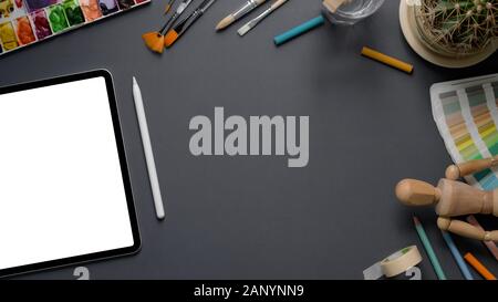 Overhead shot der Designer oder Künstler Arbeitsbereich mit Mock up Tablet, Stylus, Malwerkzeuge, und der auf dem grauen Schreibtisch Hintergrund kopieren Stockfoto