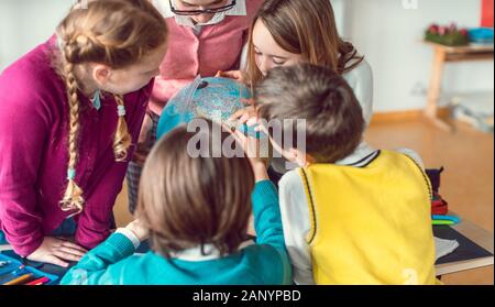 Schüler und Lehrer in der Geographie Klasse studieren ein Globus Stockfoto