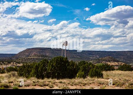 Chinle, Arizona, USA. Mai 17, 2019. Groß, rostiges Wasser Tank auf einem Turm in der Nähe der Stadt, erinnert uns an die alten westlichen USA. Hill und bewölkter Himmel Hintergrund. Stockfoto