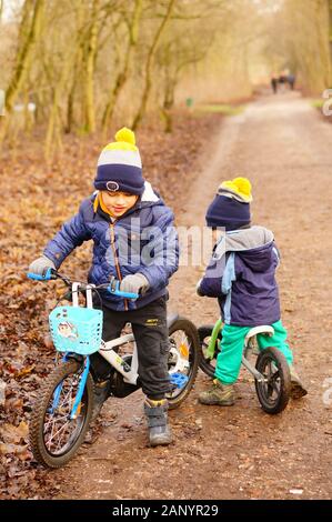 Poznan, POLEN - 13. Januar 2020: Zwei Jungen, die an einem kalten Wintertag auf einem nassen Fußweg im Wald von Debiec ein Fahrrad fahren und mit dem Fahrrad fahren. Stockfoto