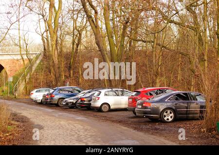 Poznan, POLEN - 12. Januar 2020: Eine Reihe von geparkten Autos in der Nähe einer Wanderroute und Bäume im Wald von Debiec. Stockfoto