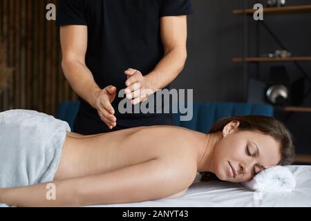 Junge, schöne Frau, die sich im Spa entspannen kann, und eine Shoudermassage im Spa. Professionelle Massagetherapeutin behandelt eine Patientin in der Wohnung.Entspannung Stockfoto