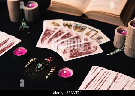 Kerzen und alte Tarotkarten auf schwarzer Seide. Halloween und Wahrsagerkonzept. Mystischer Hintergrund mit okkulten und magischen Objekten auf Hexentisch. Stockfoto