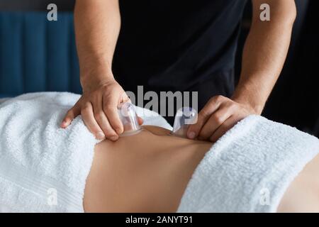 Junge schöne Frau genießen schröpfen Massage im Spa. Professionelle Massage therapeuten ist die Behandlung einer Patientin in der Wohnung. Entspannung, Schönheit, Körper Stockfoto