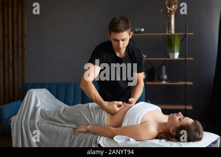Junge schöne Frau, die im Spa eine Antikellulit-Bauchmassage genießt.professionelle Massagetherapeutin behandelt eine Patientin in der Wohnung.Entspannung Stockfoto