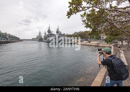 Ein junger Tourist fotografiert die australischen Marine-Schiffe, die am HMAS Kuttabul Cowper Wharf (Fleet Base East Naval Training Center) in Sydney, Australien, festgemacht sind Stockfoto