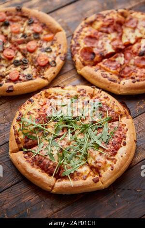 Zusammensetzung von drei verschiedenen Arten Pizza auf hölzernen Tisch Stockfoto