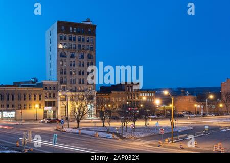 UTICA, NY - Jan 17, 2020: Closeup Antenne Nacht Blick auf die Innenstadt von Utica Straßen und Autos Spur Leuchten mit der Genesee Turm im Hintergrund. Stockfoto