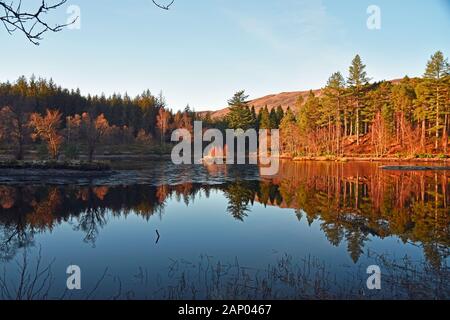 Spiegelungen der Bäume im Herbst in Glencoe lochan mit blauem Himmel Stockfoto