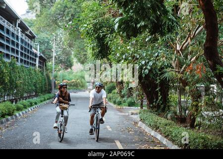 Junge Paare, die Helme tragen, genießen das gemeinsame Fahrradfahren Stockfoto