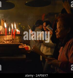 Anbeter beleuchten Räucherstäbchen und machen Opfergaben an die Götter im Mo Tempel in Hongkong. Stockfoto