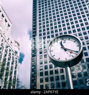 Sechs Öffentliche Uhren. Niedriger Blickwinkel auf eine der kultigen Uhren in Docklands mit Canary Wharf- und Reuters-Gebäuden im Hintergrund. Stockfoto