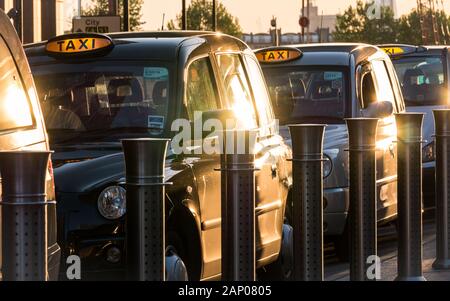 London, Großbritannien - 13. MAI 2015: Schwarze Londoner Taxi-Taxis auf einem Rang, der auf Passagiere im Geschäftsviertel Docklands wartet. Stockfoto