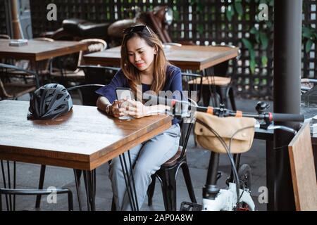 Ich habe eine lustige asiatische Frau, die ein Smartphone benutzt, wenn man im Café eine Pause macht Stockfoto