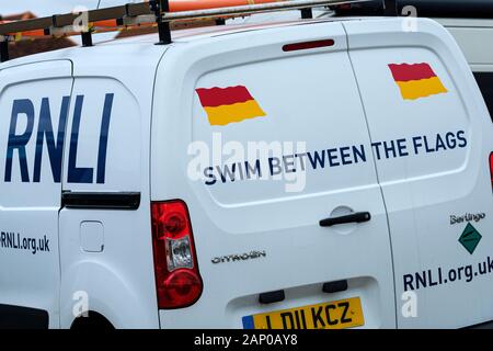 Ein rnli van am Meer mit einem signwritten Bekanntmachung Beratung schwimmen zwischen den Fahnen. Stockfoto