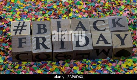 '# Black friday' geschrieben auf Holzblöcken isoliert auf Konfettihintergrund Stockfoto