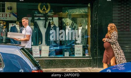 Mann, der Box vorbei gehen. shop Verkauf Anzug und schwangere Frau hinter der St Stephen grünen Gegend von Dublin in Irland. Stockfoto