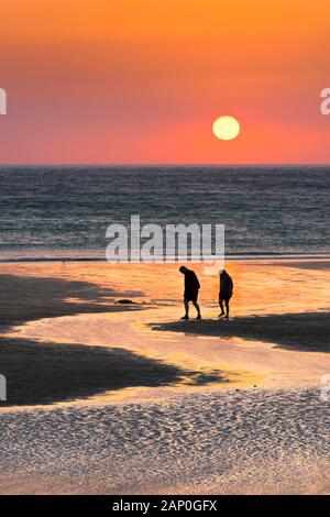 Menschen in Silhouette gegen einen schönen Sonnenuntergang am Fistral Beach in Newquay in Cornwall gesehen. Stockfoto