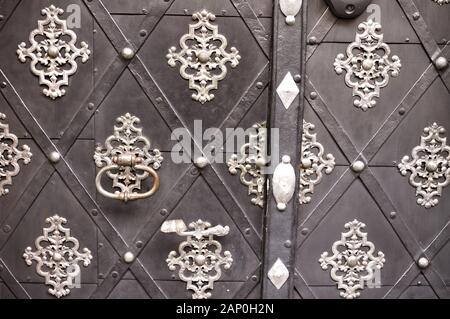 Alte Schwarze Tür mit metallischen Dekorationen und eine verrostete Klinke (Prag, Tschechische Republik, Europa) Stockfoto