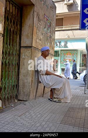 Typische Straße oder Gehweg Szene in der ägyptischen Hauptstadt Kairo: eine bawaab sitzt auf dem Nil Insel Zamalek neben dem Eingang eines Hauses und wachen auf, am 15. Juni 2019 aufgenommen. Die Funktion des Bewaab ist vielschichtig: auf der einen Seite steuert, wer das Gebäude betritt, Auf der anderen Seite er, seine Familie oder seine Helfer für die Bewohner für kleinere Dienste wie Botengänge oder einfache Reparaturen gegen eine geringe Gebühr zur Verfügung stehen. Foto: Matthias Toedt/dpa-Zentralbild/ZB/Picture Alliance | Verwendung weltweit Stockfoto