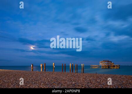 Die Nacht am Strand mit Brighton West Pier Ruinen in der Ferne. Stockfoto