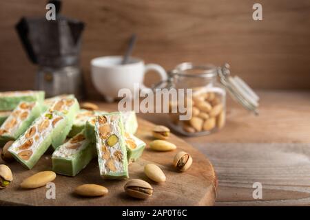 Bio Nougat mit Honig, Pistazie, Haselnuss und Mandel Mutter Muttern an einem Holztisch als Hintergrund. Stockfoto