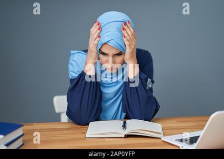 Unglücklich muslimische Studentin lernen Zuhause Stockfoto