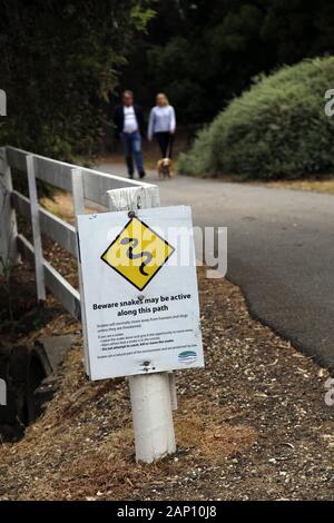 Paar Hund in der Nähe ein Zeichen Warnung der Schlangen auf dem Weg entlang der Barwon River, Geelong, Australien Stockfoto