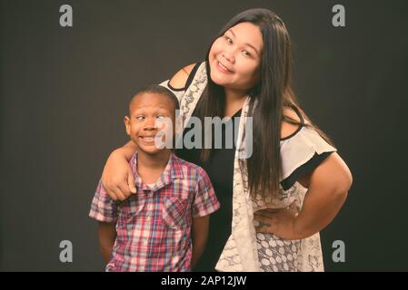 Studio schoss der schönen Übergewicht asiatische Frau und junge multi-ethnische asiatischen Jungen zusammen auf schwarzem Hintergrund Stockfoto