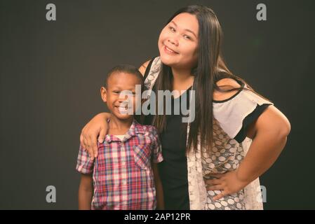 Studio schoss der schönen Übergewicht asiatische Frau und junge multi-ethnische asiatischen Jungen zusammen auf schwarzem Hintergrund Stockfoto