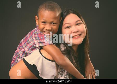 Studio schoss der schönen Übergewicht asiatische Frau und junge multi-ethnische asiatischen Jungen zusammen auf schwarzem Hintergrund Stockfoto