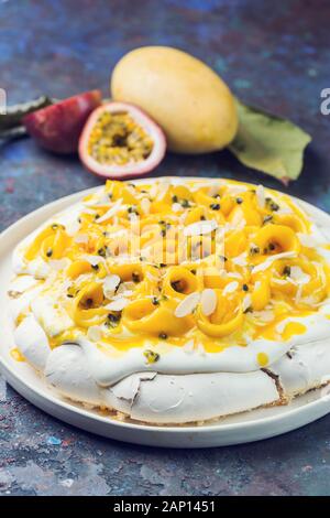 Baiser Torte Pavlova mit frischer Mango und Passionsfrucht und Schlagsahne auf Schiefer, Stein oder Beton Hintergrund Stockfoto