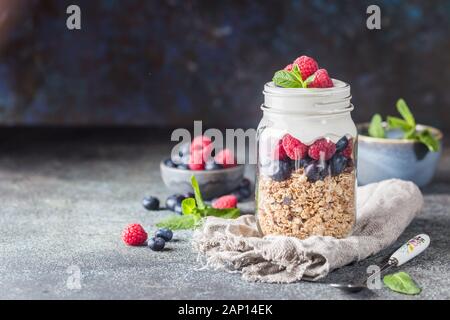 Müsli Parfait mit Joghurt, Haferflocken Müsli, frische Beeren, Honig und Minze im hohen Glas, kopieren Raum Stockfoto