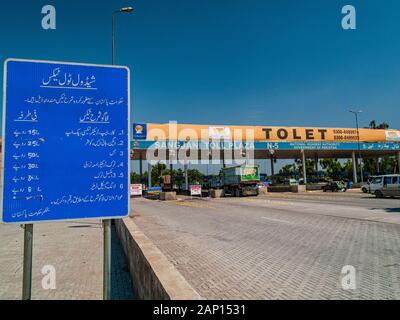 Straßenschild mit arabischer Schrift und Mautstation am Autobahnbeginn Stockfoto