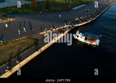 Istanbul, Türkei - 15. September 2019: Menschenmenge und ein Fischerboot an der Küste des Goldenen Horns auf Holzboden in Sonnenuntergang aus der Luft. Stockfoto