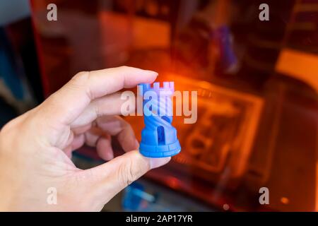 Hand mit Kunststoff Schachfigur auf 3d-Drucker in der Nähe gedruckt - oben Stockfoto