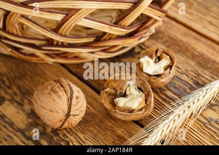 Die Walnüsse in der Nähe, Weizen Ohr und Weidenkorb auf alten Brettern. Geringe Tiefenschärfe. Ansicht von oben. Stockfoto