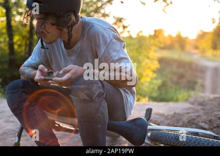 Menschen, Sport, aktiven Lebensstil und moderner Technologie. Outdoor Bild der Radfahrer auf Booster Bike mit Navigator auf Smart Phone, Karte erkunden und s Stockfoto