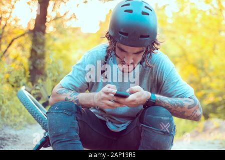 Menschen, Sport, aktiven Lebensstil und moderner Technologie. Outdoor Bild der Radfahrer auf Booster Bike mit Navigator auf Smart Phone, Karte erkunden und s Stockfoto