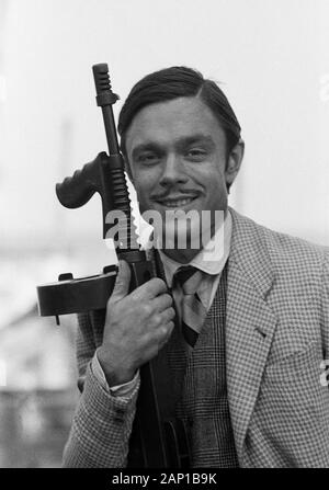 Jürgen Drews, deutscher Schlagersänger, mit Maschinengewehr als Mafioso, Deutschland um 1980. Deutsche Schlager Sänger Jürgen Drews spielen eine Mafia Mitglied mit einem Maschinengewehr, Deutschland um 1980. Stockfoto