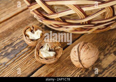 Close-up Walnüsse und Weidenkorb auf alten Brettern. Geringe Tiefenschärfe. Ansicht von oben. Stockfoto