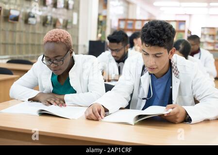 Eine Gruppe von jungen Medizinstudenten mit mixed-race Chirurgen untersucht diese Vorgänge in einem Laptop. Stockfoto