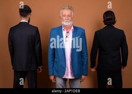 Drei multi-ethnische bärtigen Geschäftsmänner gemeinsam gegen braunen Hintergrund Stockfoto