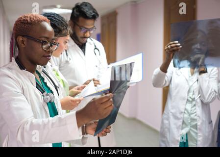 Medizinische Studenten, Praktikanten. Junge Ärzte, gemischten Rennen, auf dem Flur des Krankenhauses, Beratung. X-ray Bilder von Patienten untersucht, medizinische Pr Stockfoto