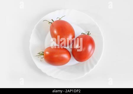 Rote reife saftige Tomaten auf einem weißen Teller. Hellgrauen Hintergrund Stockfoto
